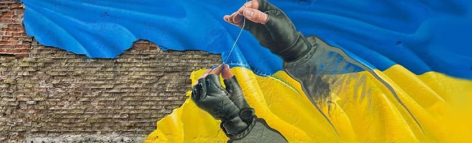 Мурал: руки військового зшивають український прапор на цегляній стіні